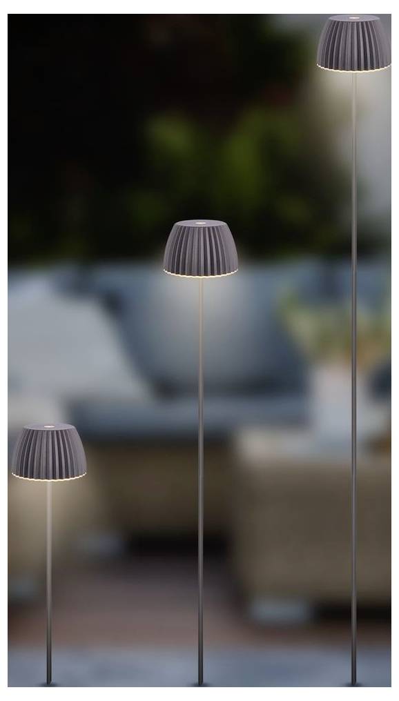 Tri štíhle vonkajšie stojace lampy so sivými rebrovanými tienidlami v rôznych výškach, jemne osvetlené na pozadí rozmazaného patia.