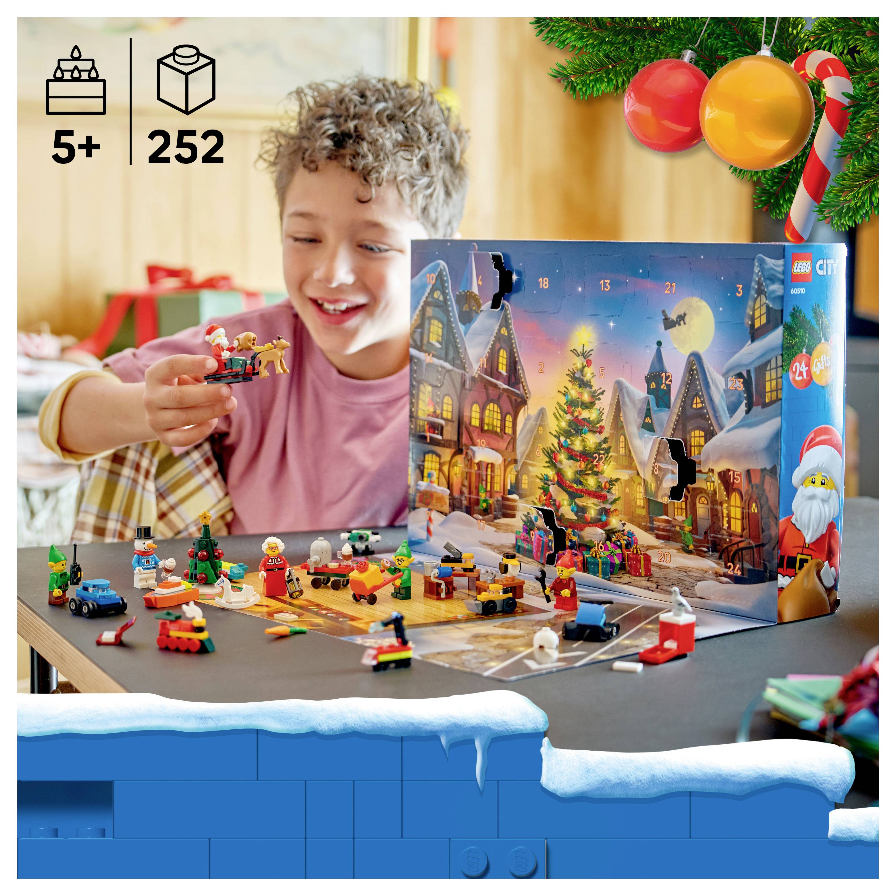 Dieťa otvára adventný kalendár LEGO City s odporúčanou vekovou kategóriou 5+ rokov a 252 časťami, v ruke drží malú figúrku hračky medzi rozptýlenými mini stavbami na slávnostnom stole.
