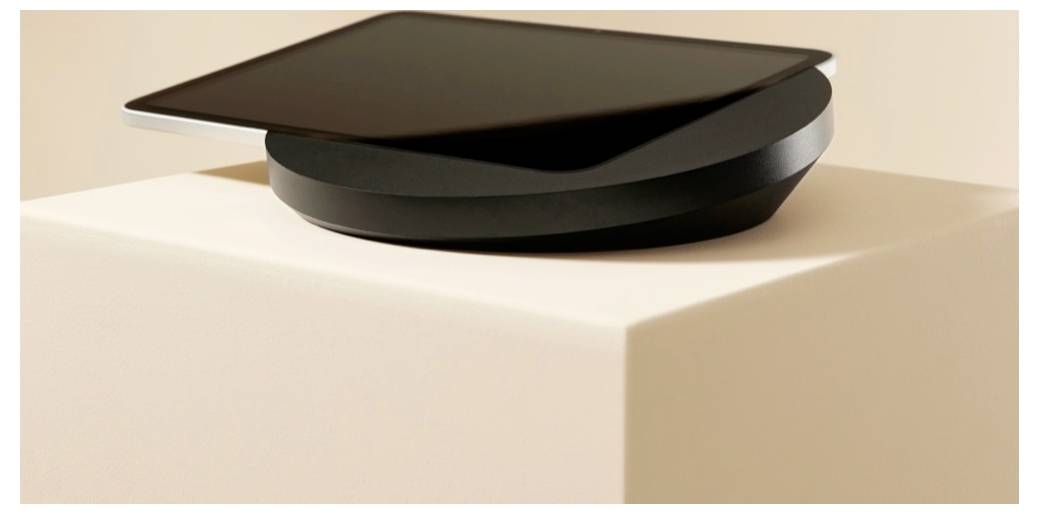 Čierny moderný prístroj alebo socha so zloženými zakrivenými vrstvami, spočívajúca na bielom podstavci v mäkkej študijnej osvietlení.