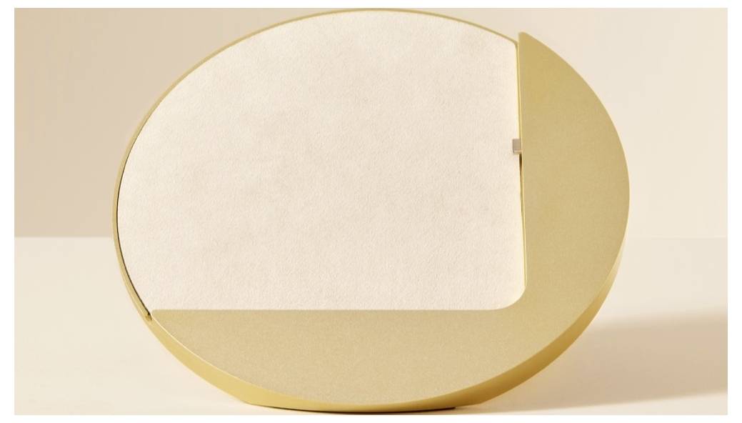 Abstraktný zlatý oválny rám s prázdnym kremovým stredom, ako minimalistický dekoratívny štítok alebo tabuľka na neutrálnom pozadí.