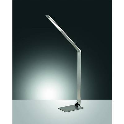 Moderná strieborná nastaviteľná stolová lampa stojaca na podstavcoch, rozsvietená na tmavom pozadí.
