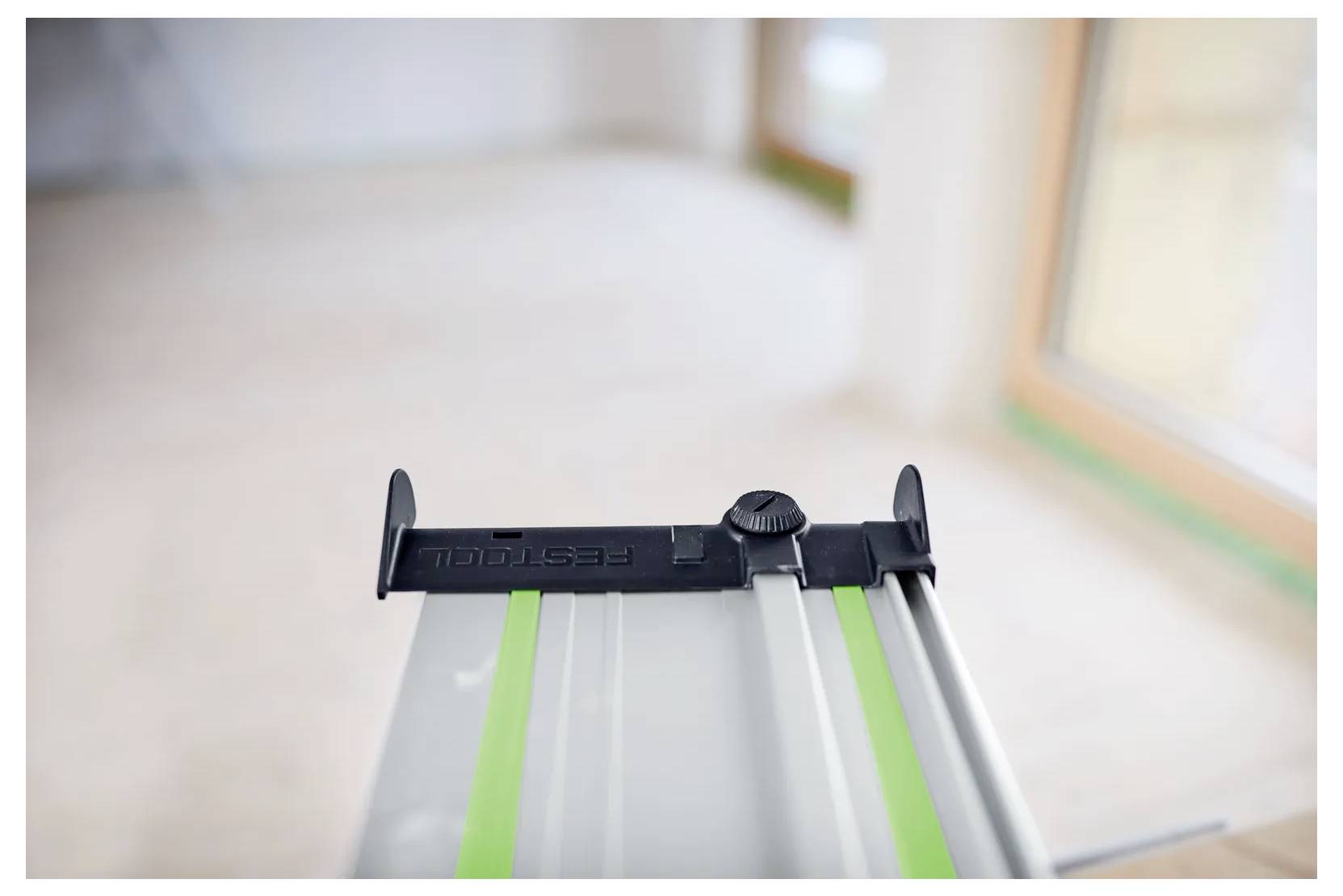 Detailný zábehr na vodiacej lište Festool kotúčovej píly so zelenými pruhmi, zobrazený v jasno osvetlenej interiérovej miestnosti počas rekonštrukcie.