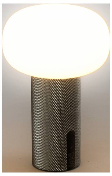 Malá valcová stolná lampa so svietiacou oválnou bielou tienidlom a textúrovanou tmavou kovovou podstavou, zobrazená na jednoduchom pozadí.