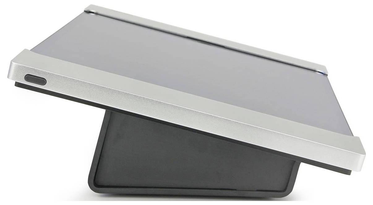 Zatvorený strieborný notebook alebo tablet s tmavou základňou, zobrazený pod uhlom na bielom pozadí.