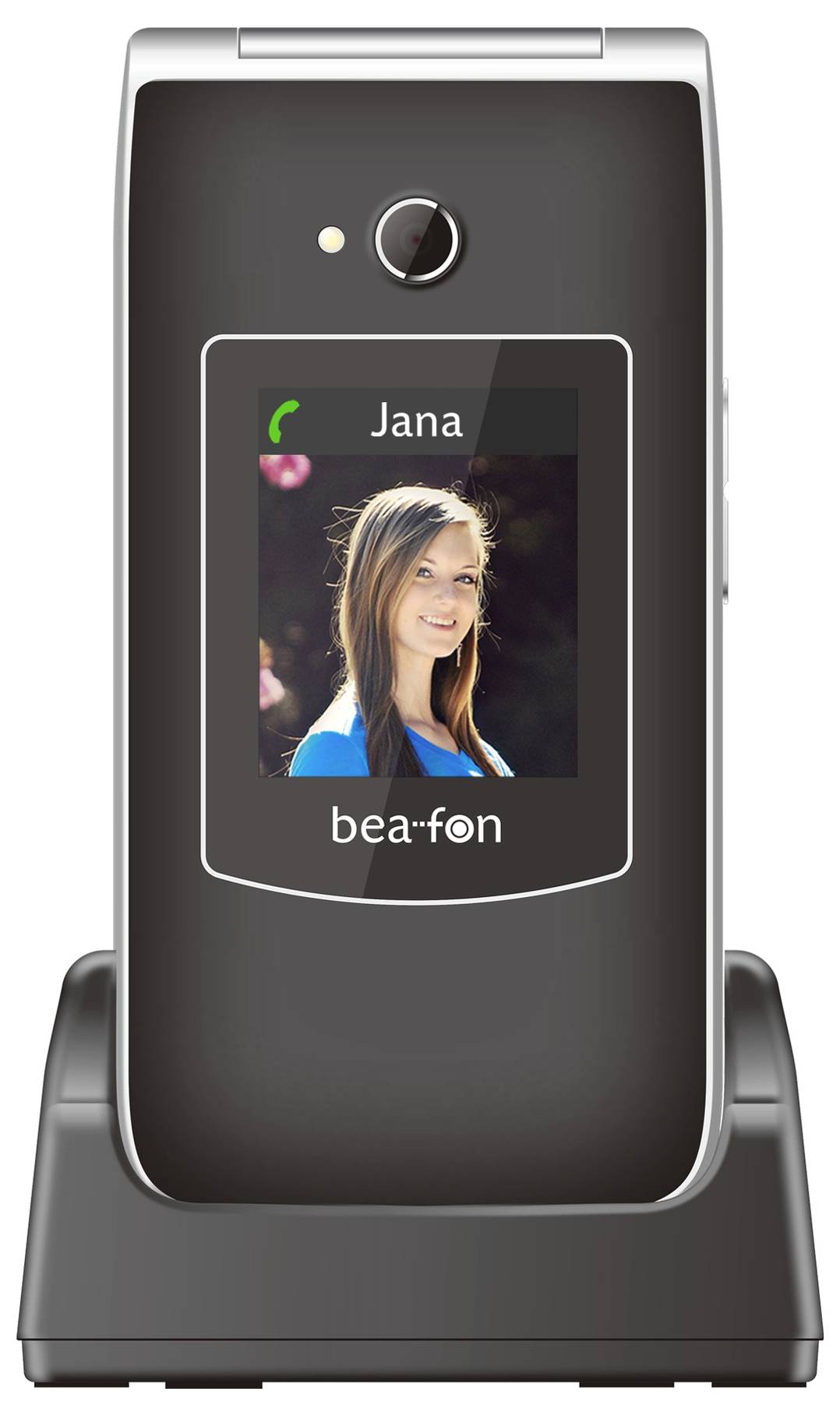 Zatvorený mobilný telefón na nabíjacej dokovej stanici, zobrazujúci obrazovku hovorcu s názvom kontaktu "Jana" a fotografiou ženy.