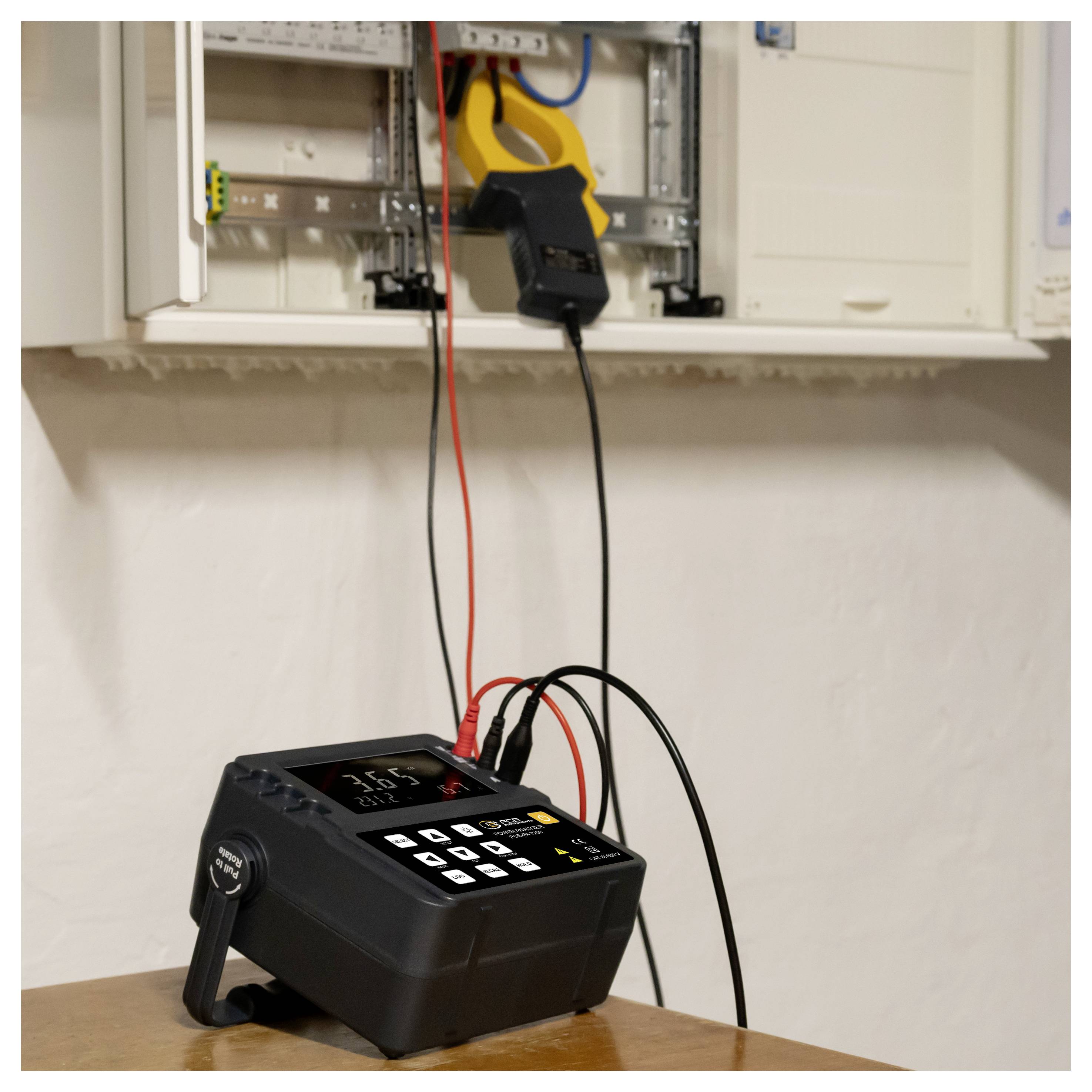 Prenosné elektrické testovacia zariadenie na stole pripojené kábľami k otvorenej nástennej elektrickej rozvodnici, ktoré indikuje testovanie živého obvodu.