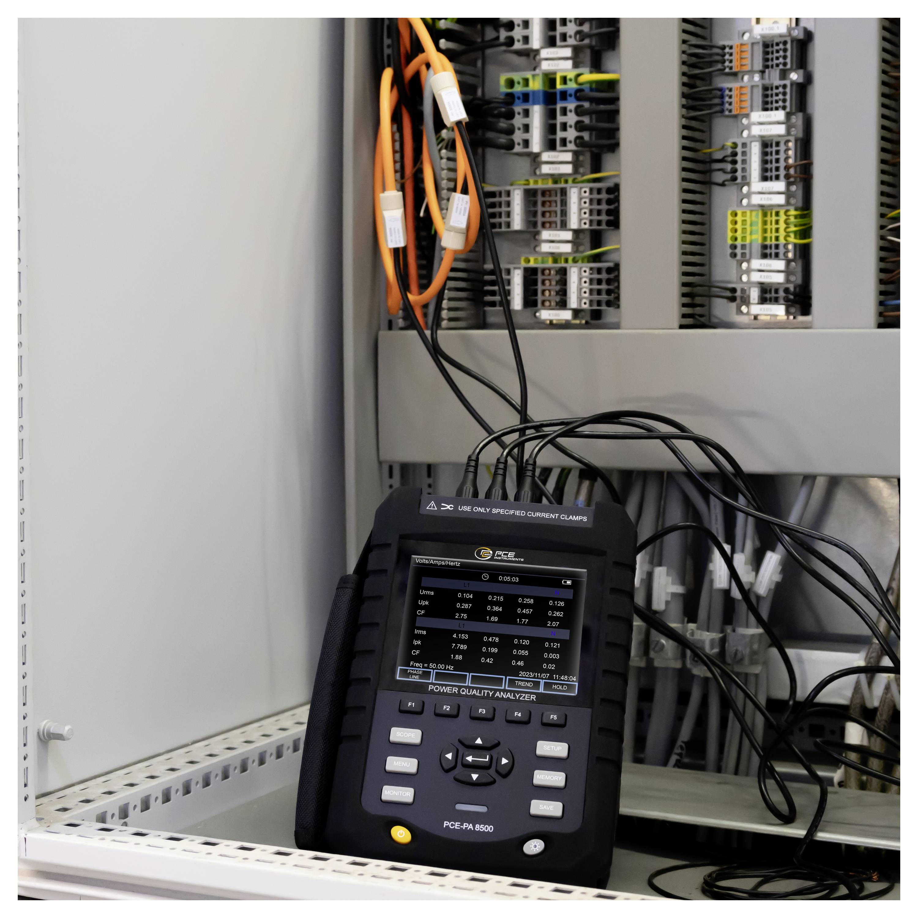 Prenosný analyzátor kvality elektrickej energie pripojený kabelmi vnútri elektrickej rozvádzačovej skrine s obvodovými modulmi a vedením.