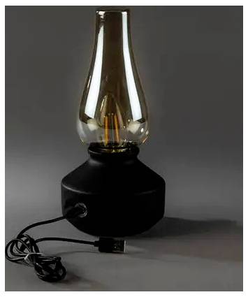 Vintážna stolná lampa s čírym skleneným komínom a čiernym podstavcom, zobrazená s navíjaným napájacím kábľom v popredí na jednoduchom sivom pozadí.
