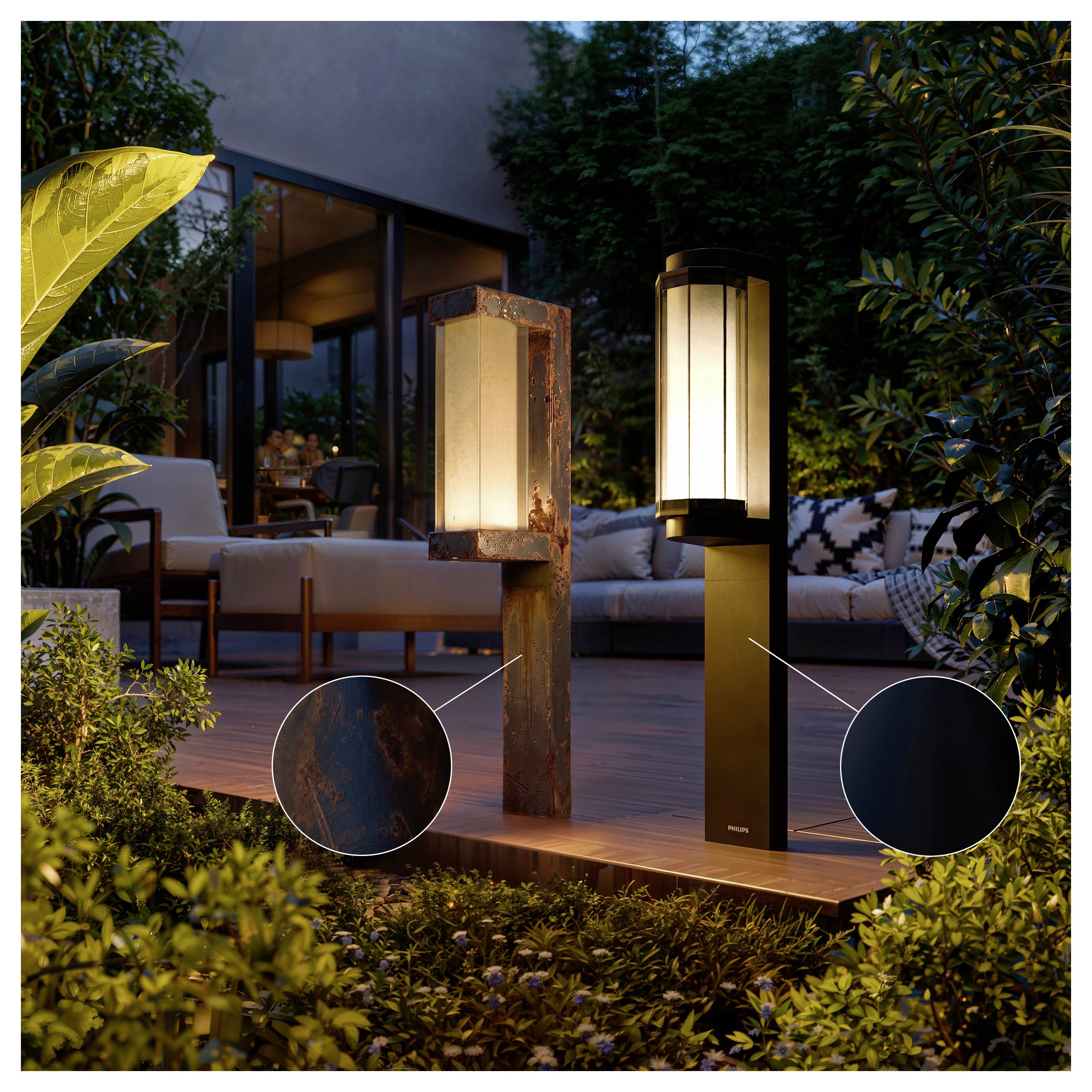 Exteriérová scéna terasy s dvoma modernými svetlami so stĺpikom, jedným z patinovaného kovu a jedným čiernym so teplými svietiacimi panelmi, vedľa oddychovacieho sedenia a zelene.