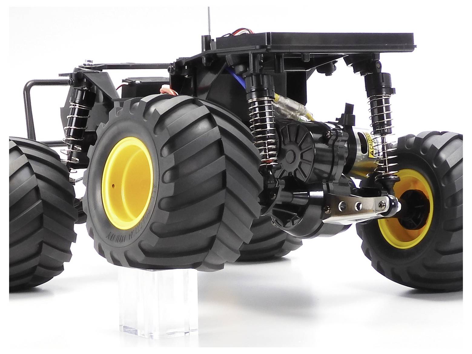 Pohľad spodnej časti diaľkovo ovládaného terénneho vozidla buggy s veľkými hrčavými pneumatikami a exponovaným zavesením na bielom pozadí.