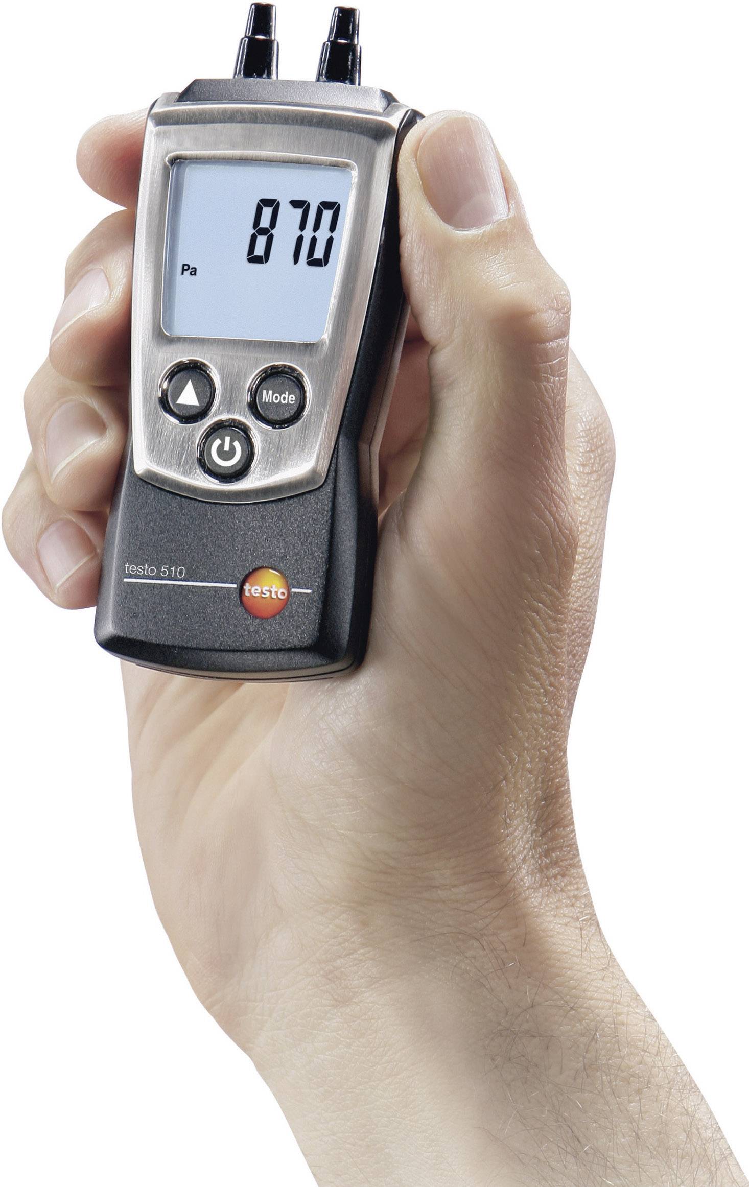 Jedna ruka drží digitálny manometer, ktorý zobrazuje '870 Pa'. Zariadenie sa zjavne používa na meranie tlaku.