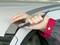 Osoba používa modré plastové náradie, aby opatrne otvorila tesnenie autového okna.