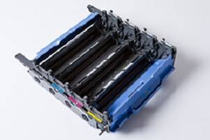 Obrázok prázdneho držiaka atramentových kaziet so štyrmi otvormi. Dva modré bočné kryty. Pohľad zhora na bielom pozadí.