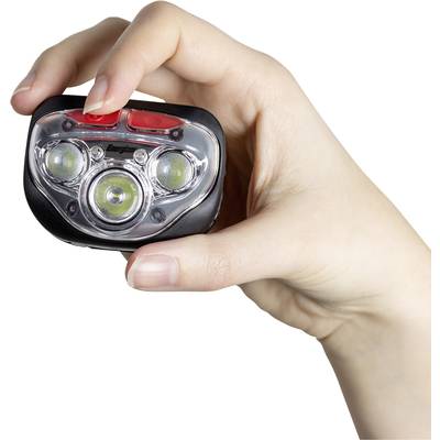 Jedna ruka drží malú LED baterku. Predná strana lampy ukazuje tri svietiace LED diódy a červené tlačidlá hore.
