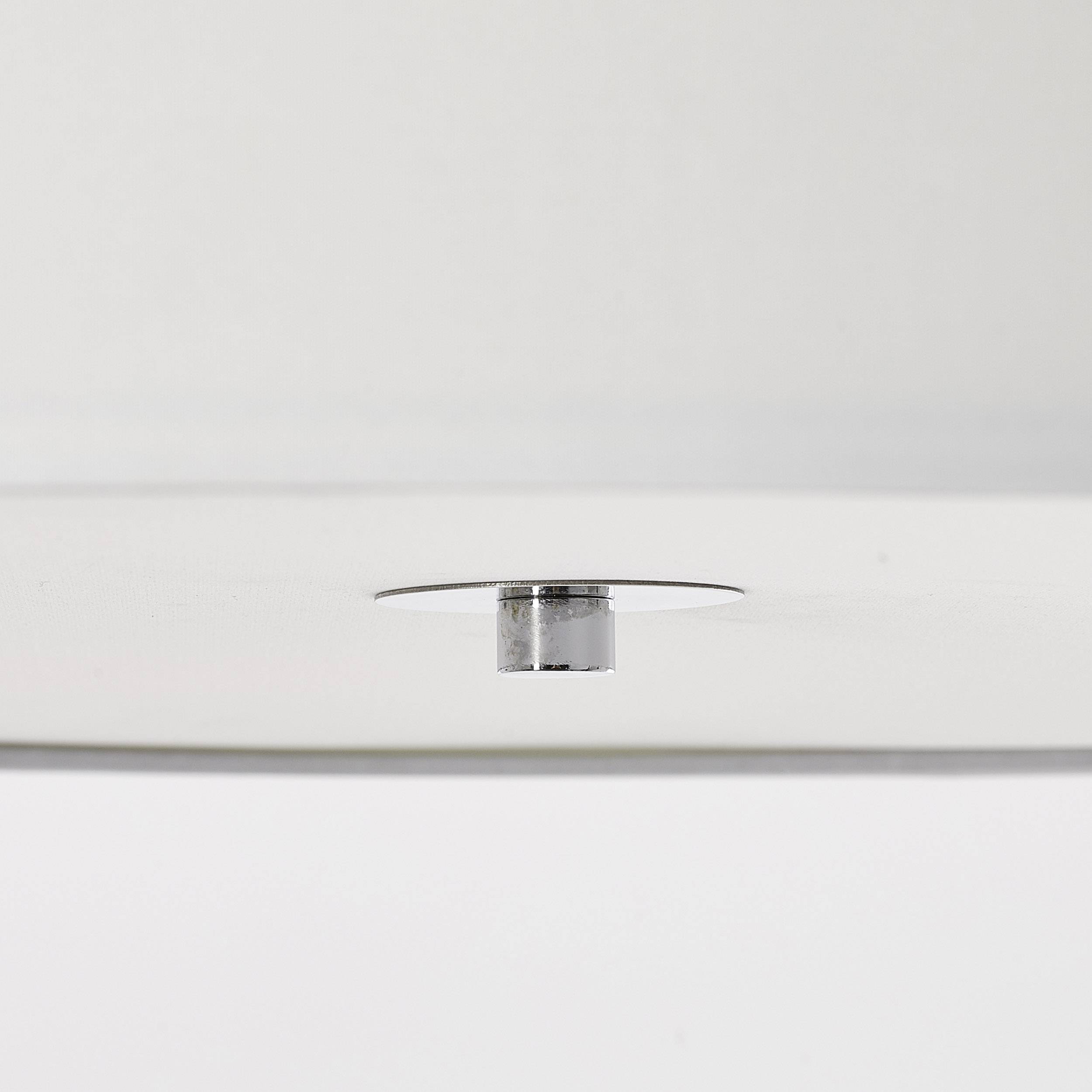 Detailný pohľad na biely štruktúrovaný stropný povrch s malým, okrúhlym, strieborným výstupkom alebo gombíkom v strede.