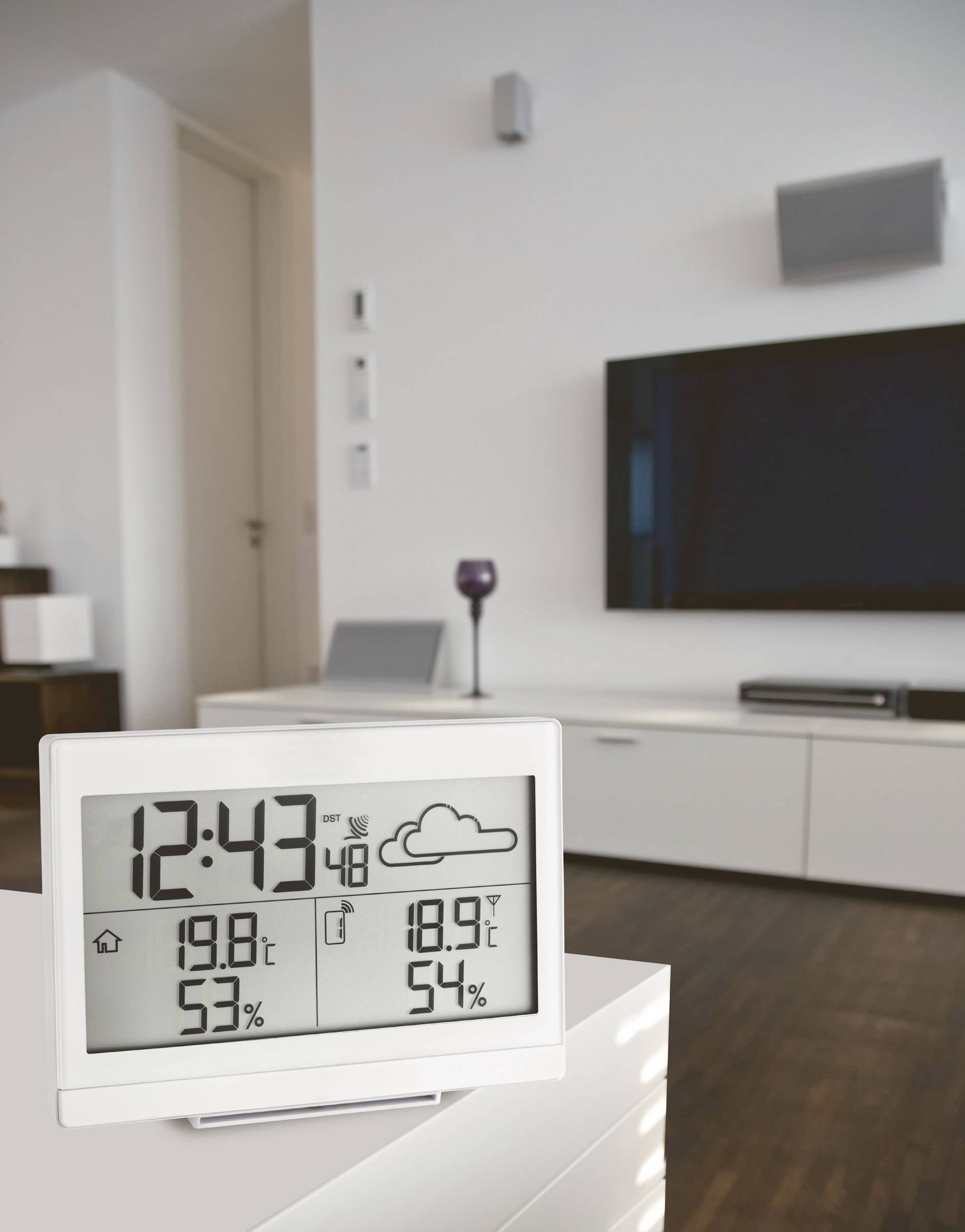Digitálny teplomer v obývacej izbe ukazuje vnútornú teplotu 19,8°C, vlhkosť vzduchu 53% a predpoveď počasia so symbolom oblakov.