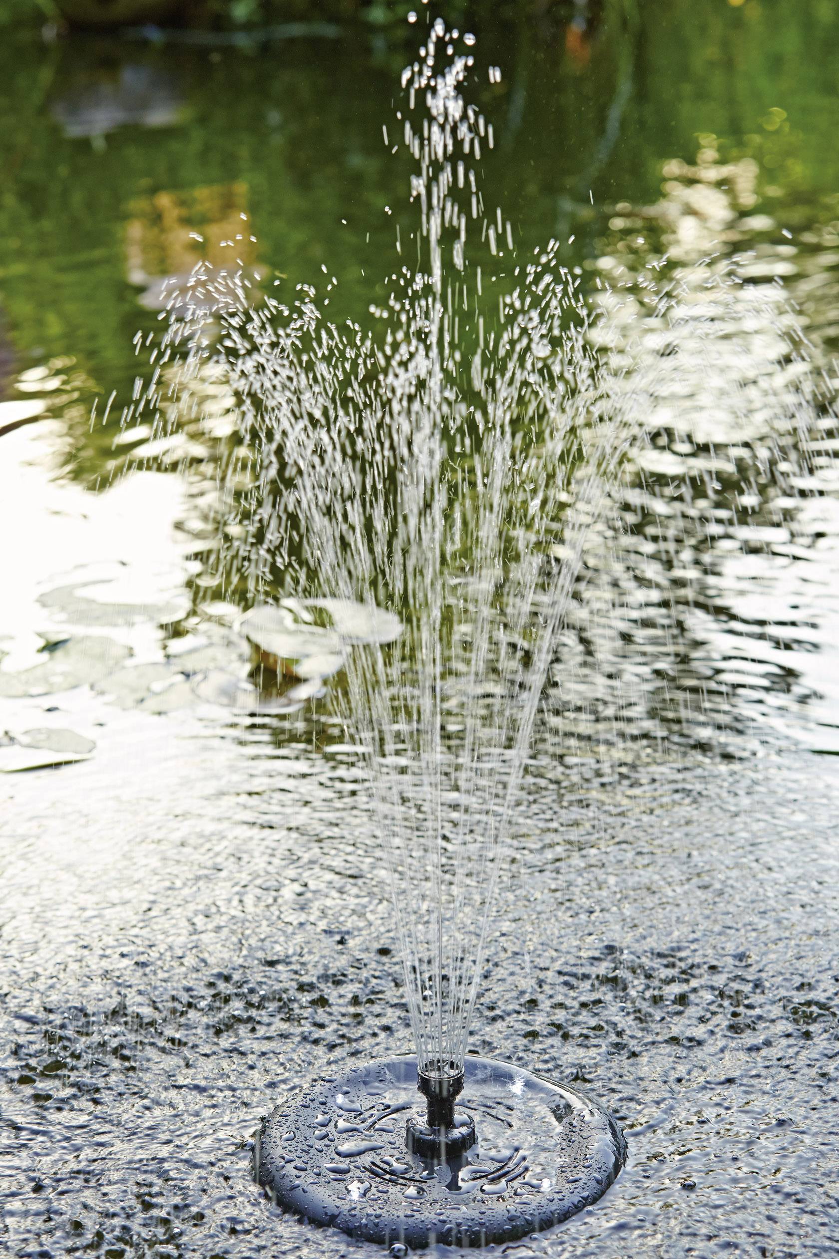 Malá fontána striekajúca vodu do vzduchu nad jazerom v zelenom prostredí.