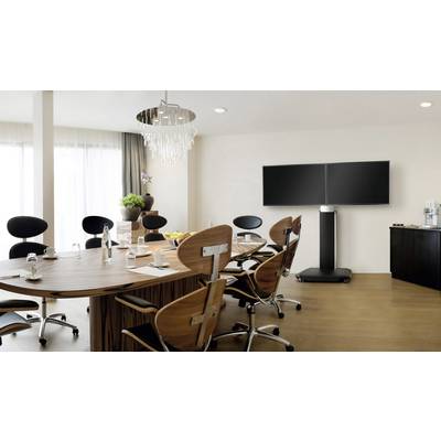 Rokovacia miestnosť s veľkým dreveným stolom, modernými stoličkami, dvoma veľkými obrazovkami na stojane a rastlinnou dekoráciou.