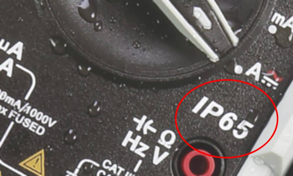 Multimeter s ochranným krytím IP65, obklopený vodnými kvapkami, znázorňuje odolnosť proti vode.