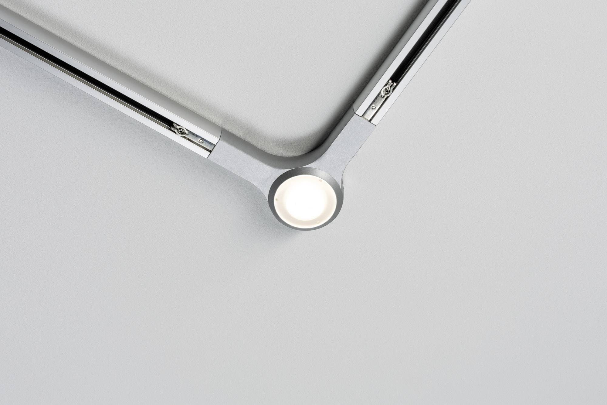 Roh modernej stropnej lampy z kovu, ktorá vyžaruje jasné, priame svetlo pred sivým pozadím.