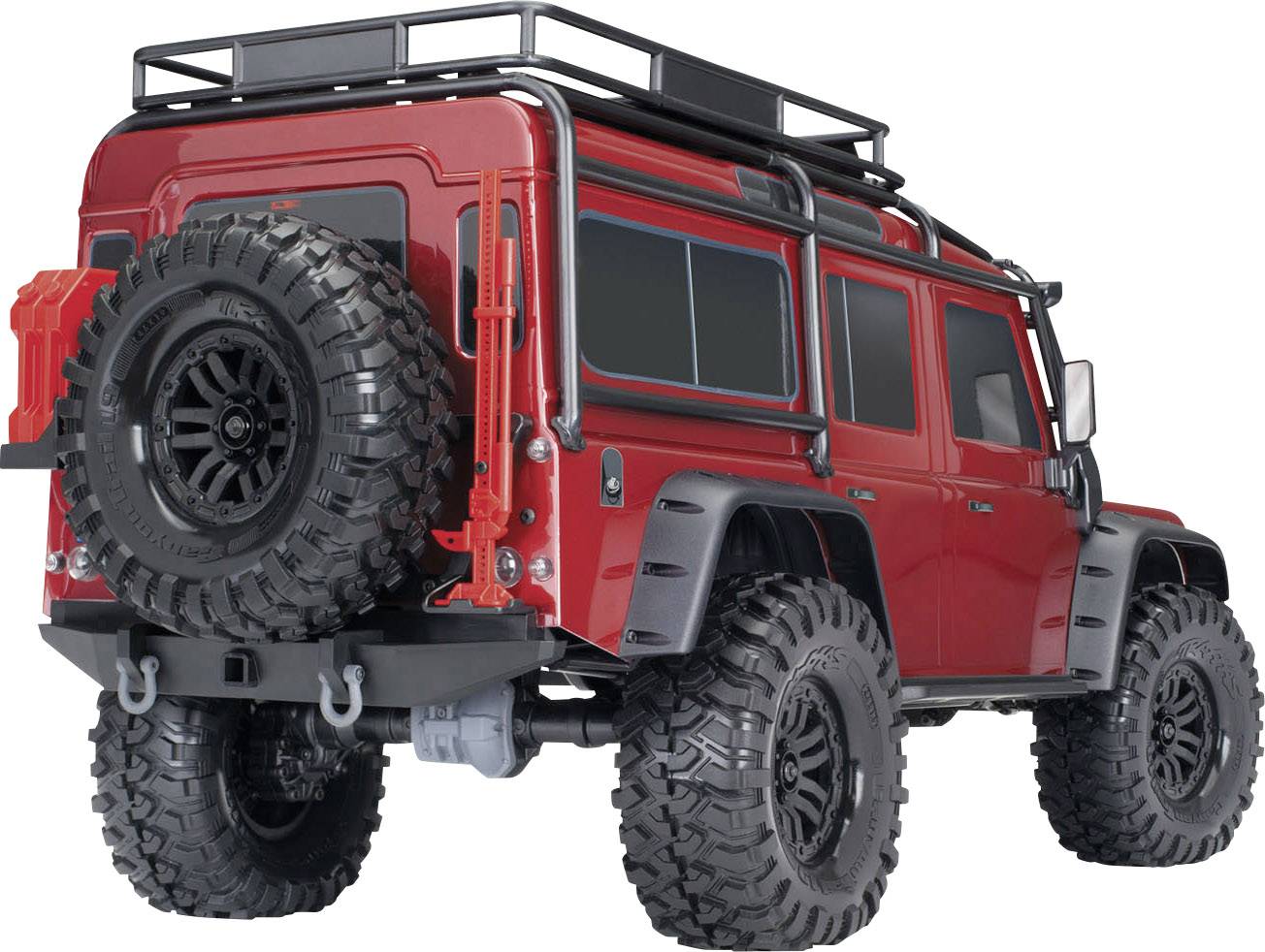 Červené terénne modelové auto s veľkými offroad pneumatikami, náhradným kolesom a strešným nosičom, fotografované z pohľadu zozadu.