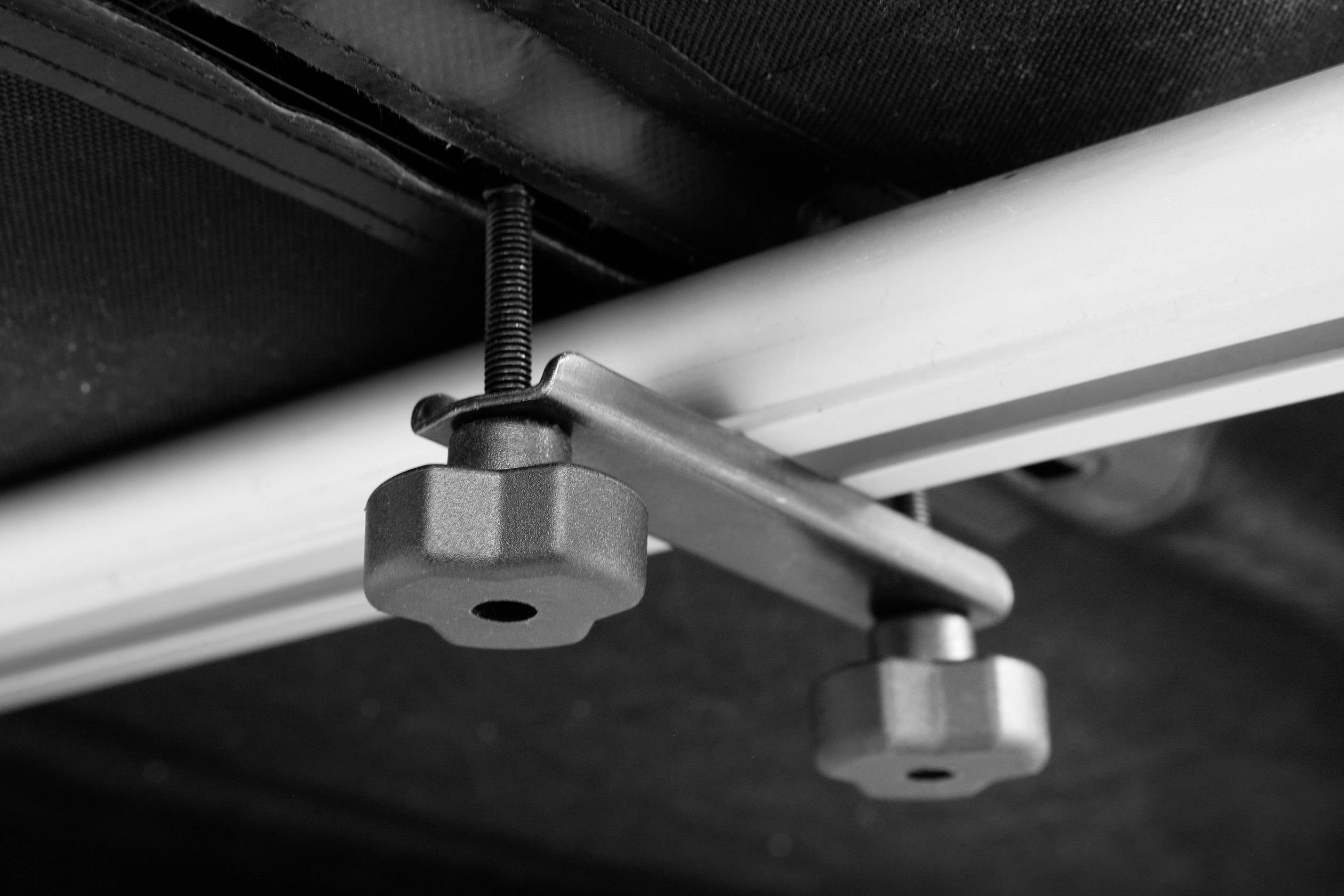 Detailný záber svorky na koľajnici s čiernym pozadím.