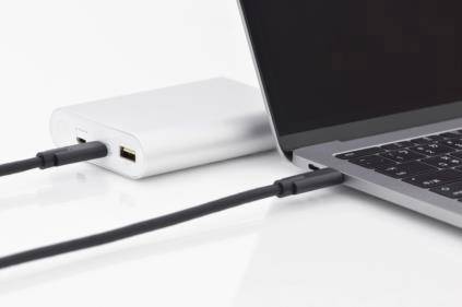 Laptop je napájaný powerbankou. Kábel prepája powerbankua laptop na bielom pozadí.