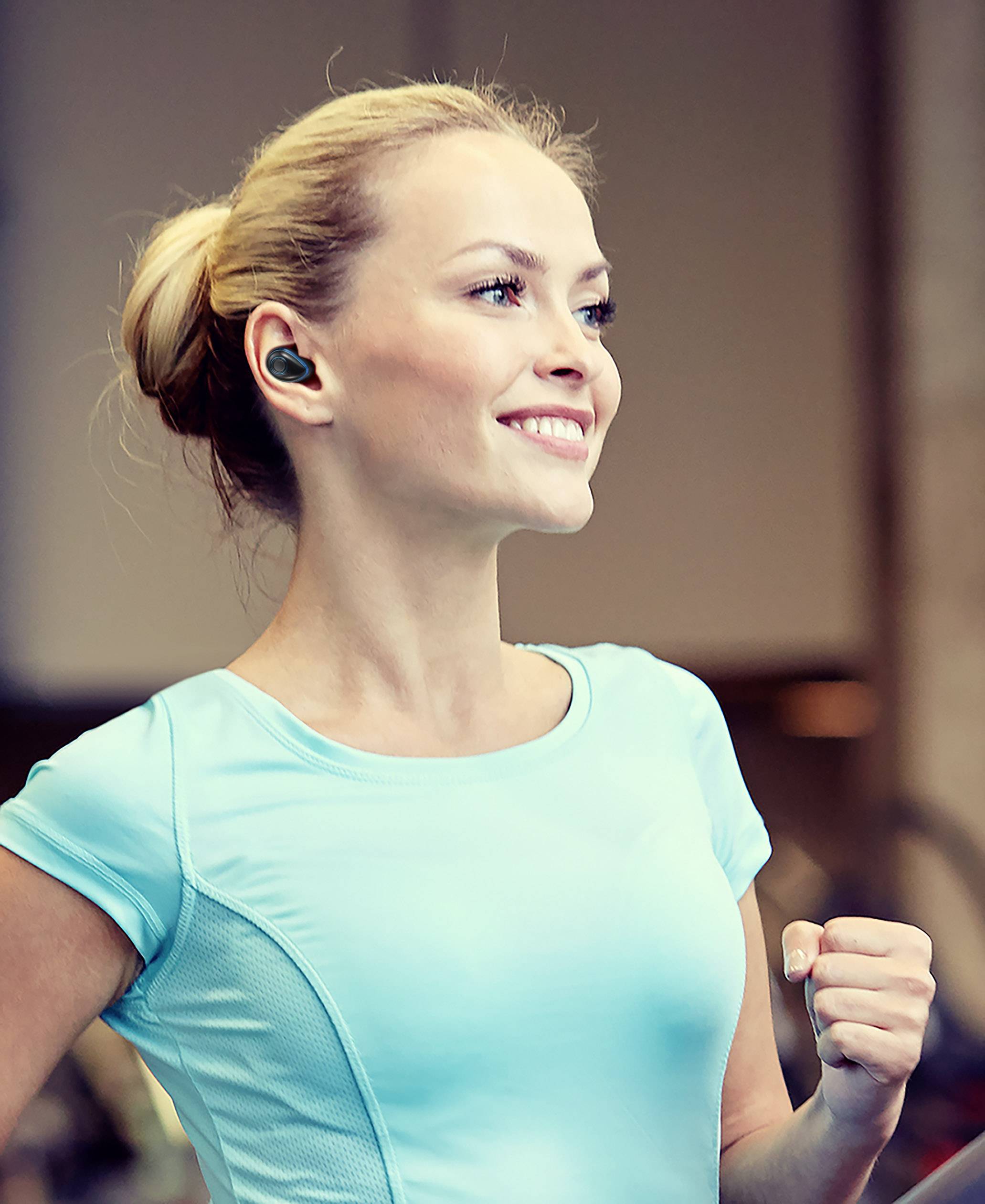 Усmiata žena v športovom oblečení s bezdrôtovými slúchadlami beží vnútri.