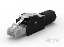 RJ45 konektor, čiastočne obalený čiernym plastom, leží na bielom povrchu. Logo spoločnosti TE Connectivity je viditeľné.