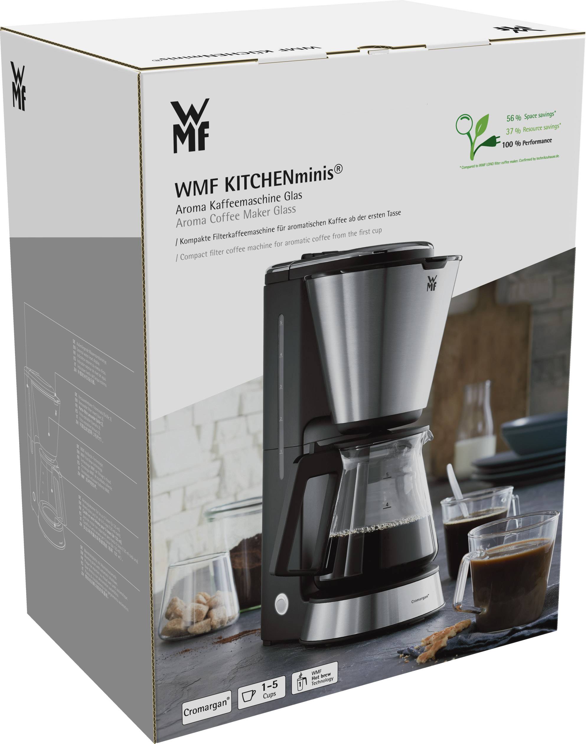 Balenie kávového prístroja WMF KITCHENminis Aroma so sklenenou nádobou a povrchom Cromargan. Obrázok zobrazuje prístroj a kávové šálky na stole.