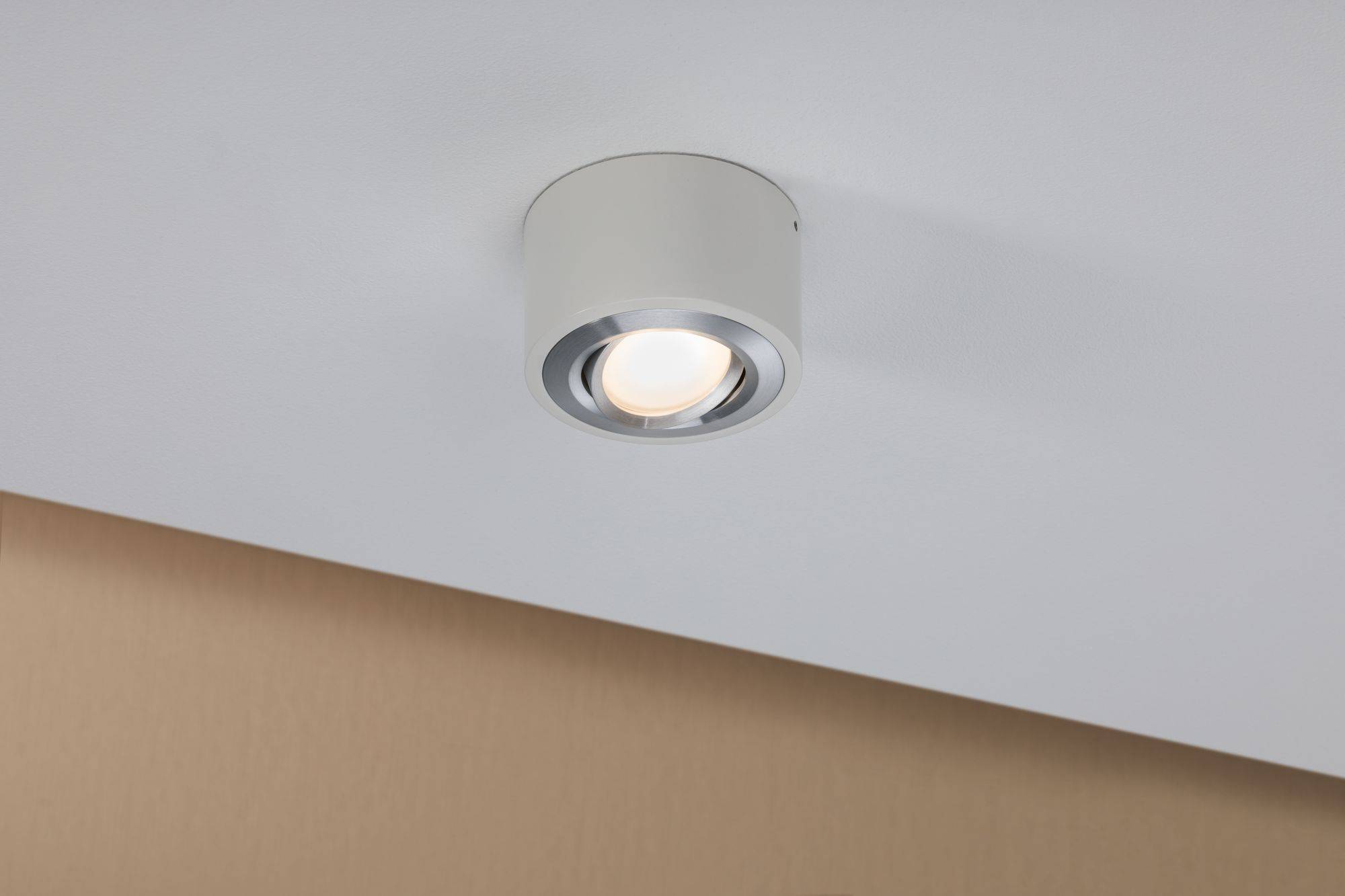 Biela strieborná stropná lampa vyžaruje teplé svetlo v jednoduchej miestnosti.