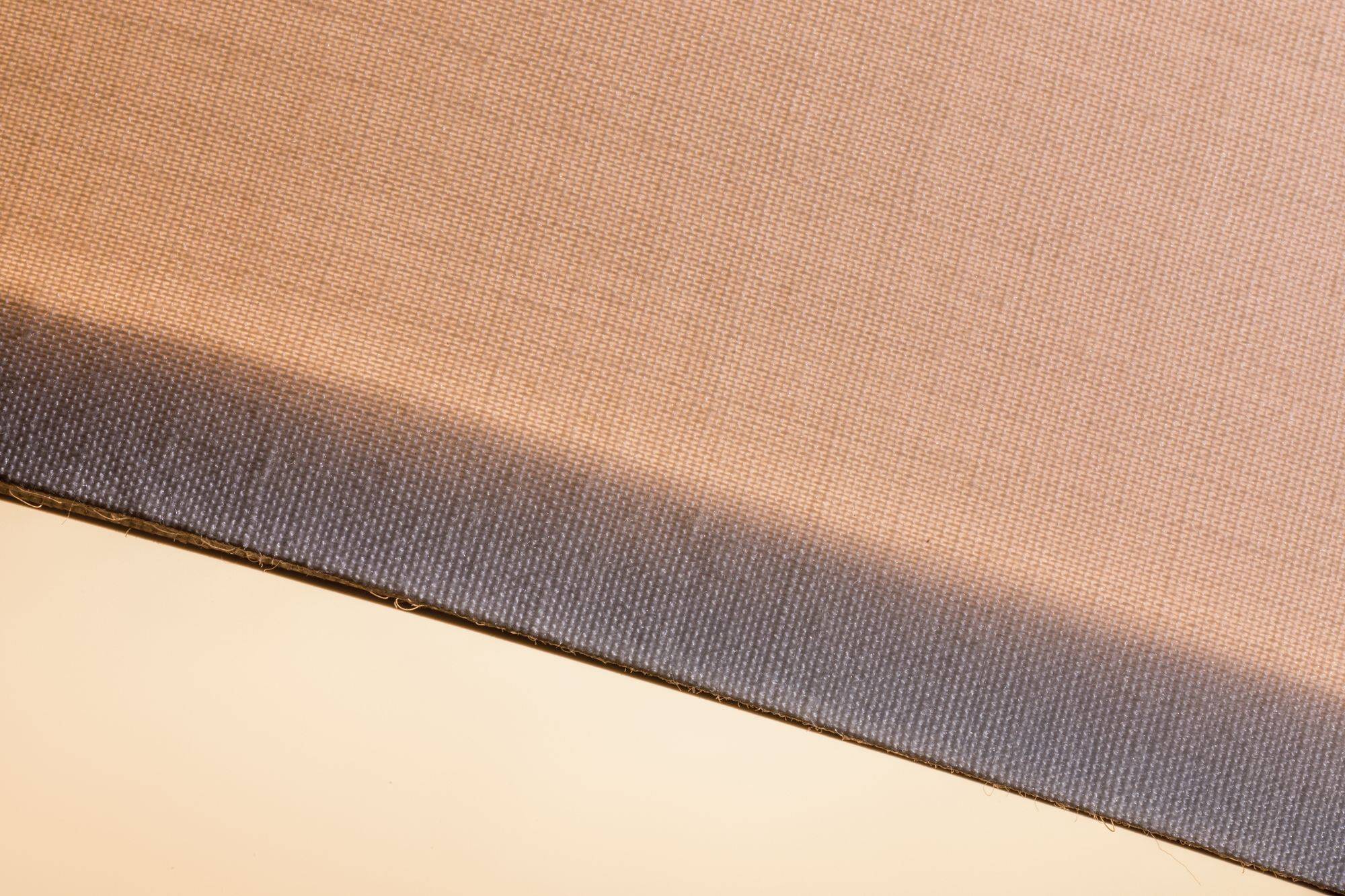 Detailný záber na dvojfarebný textil. Spodná časť je tmavšia, horná svetlejšia. Zobrazuje textúru a farebný prechod.