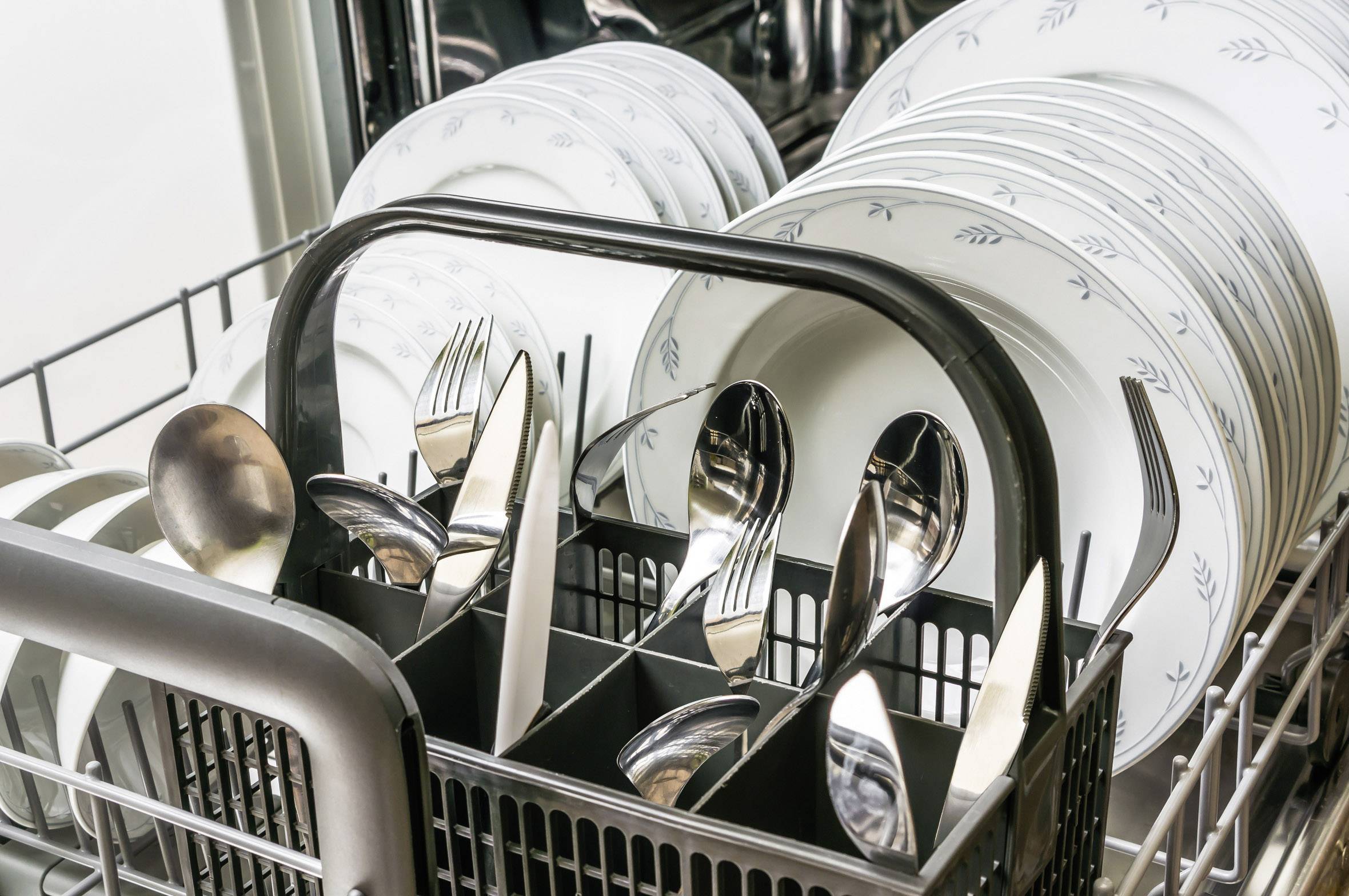 Plne naložená umývačka riadu s čistým riadom a príborom, pripravená na vyloženie po umývacom cykle.