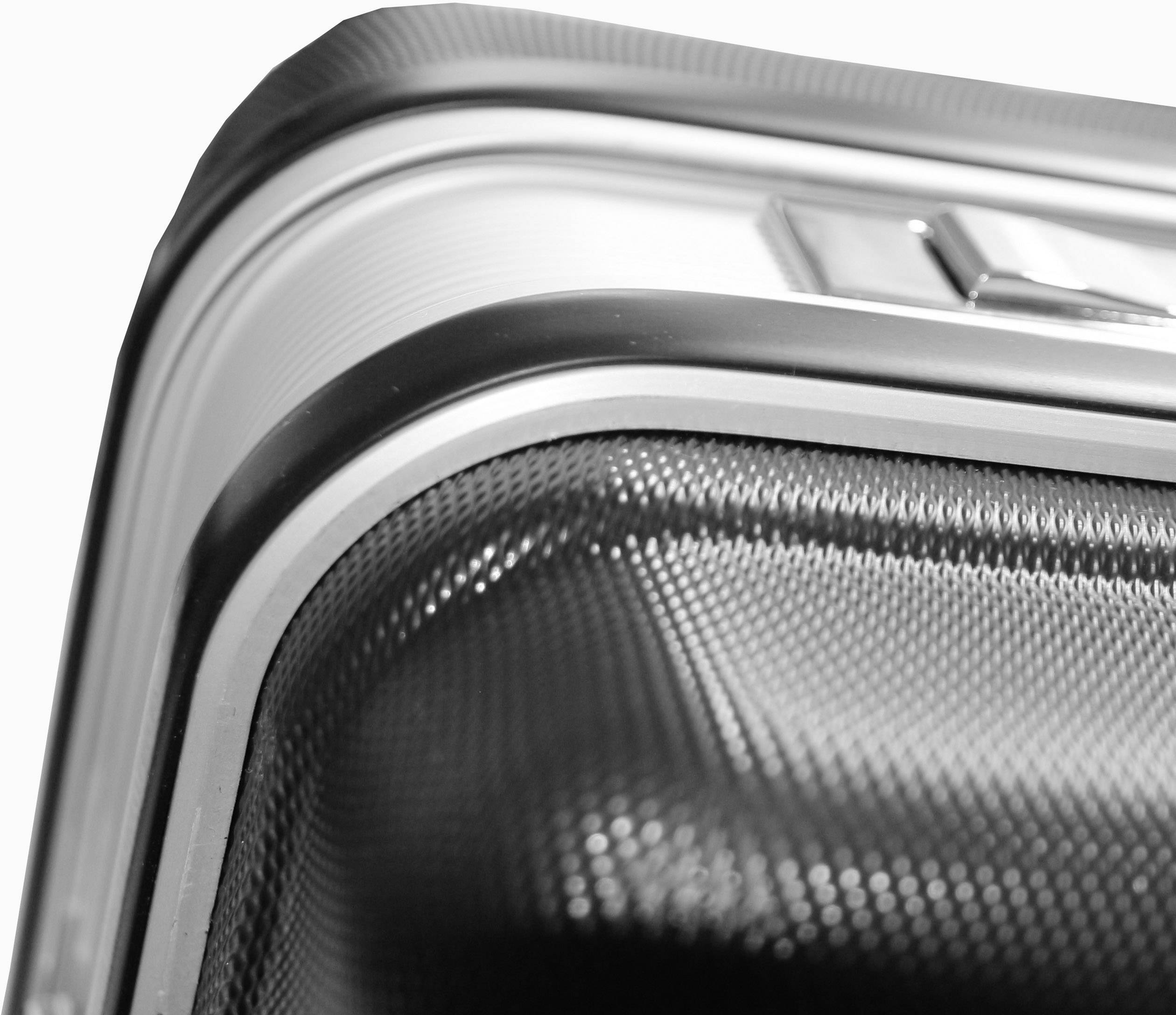 Vzpriamený, štruktúrovaný kufor s kovovými akcentmi. Detaily povrchu a zaoblené rohy sú viditeľné.