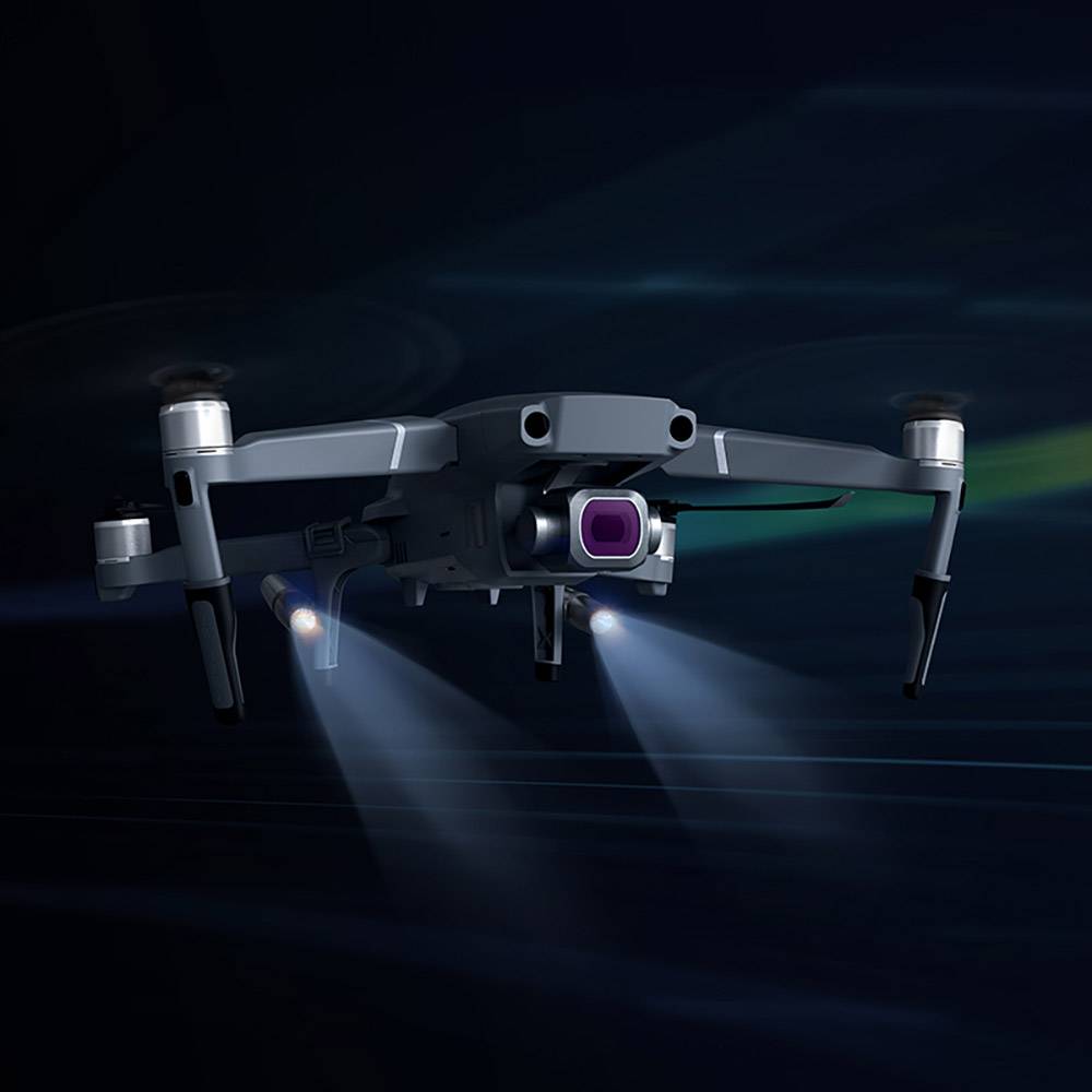 Dron letí obklopený tmavým pozadím. Jeho svetlá sú zapnuté, čo vytvára technologický a futuristický dojem.