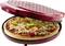 Pizza s pestrofarebnou zeleninou a syrom sa pečie v okrúhlej červenej peci na pizzu.