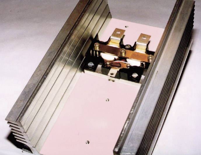 Kovový chladič s pripevnenými elektronickými súčiastkami, pravdepodobne určený na odvod tepla v elektronických zariadeniach.
