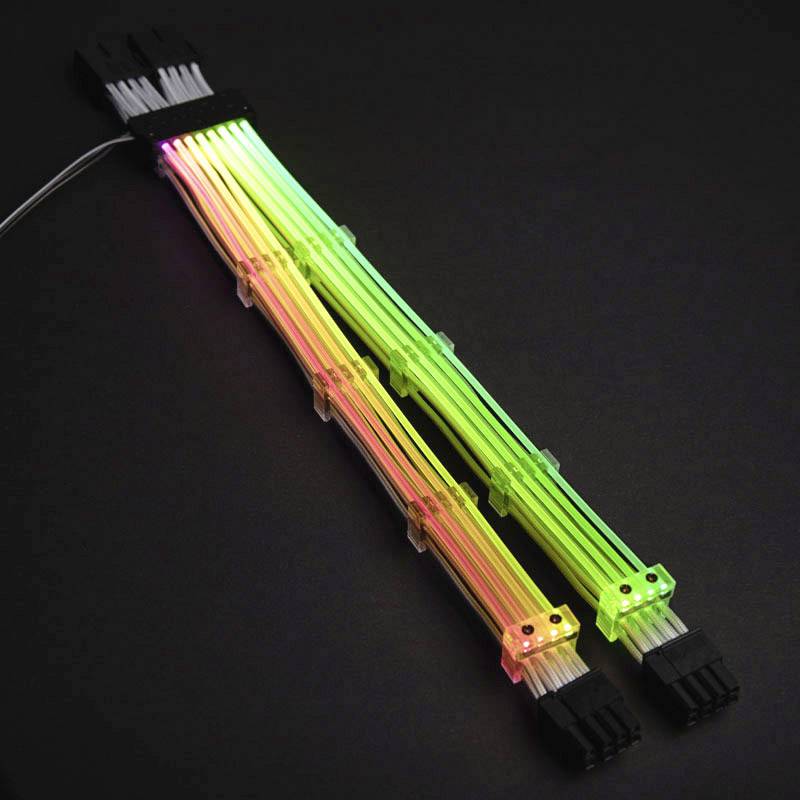 Svietiace, viacfarebné LED káble so širokým konektorom na čiernom pozadí. Káble v zelnej, žltej a červenej farbe.