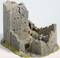 Miniaturový model starej zrúcaniny hradu s štruktúrovanými kamennými stenami a čiastočne zrútenými múrmi na zazelenalej základni.