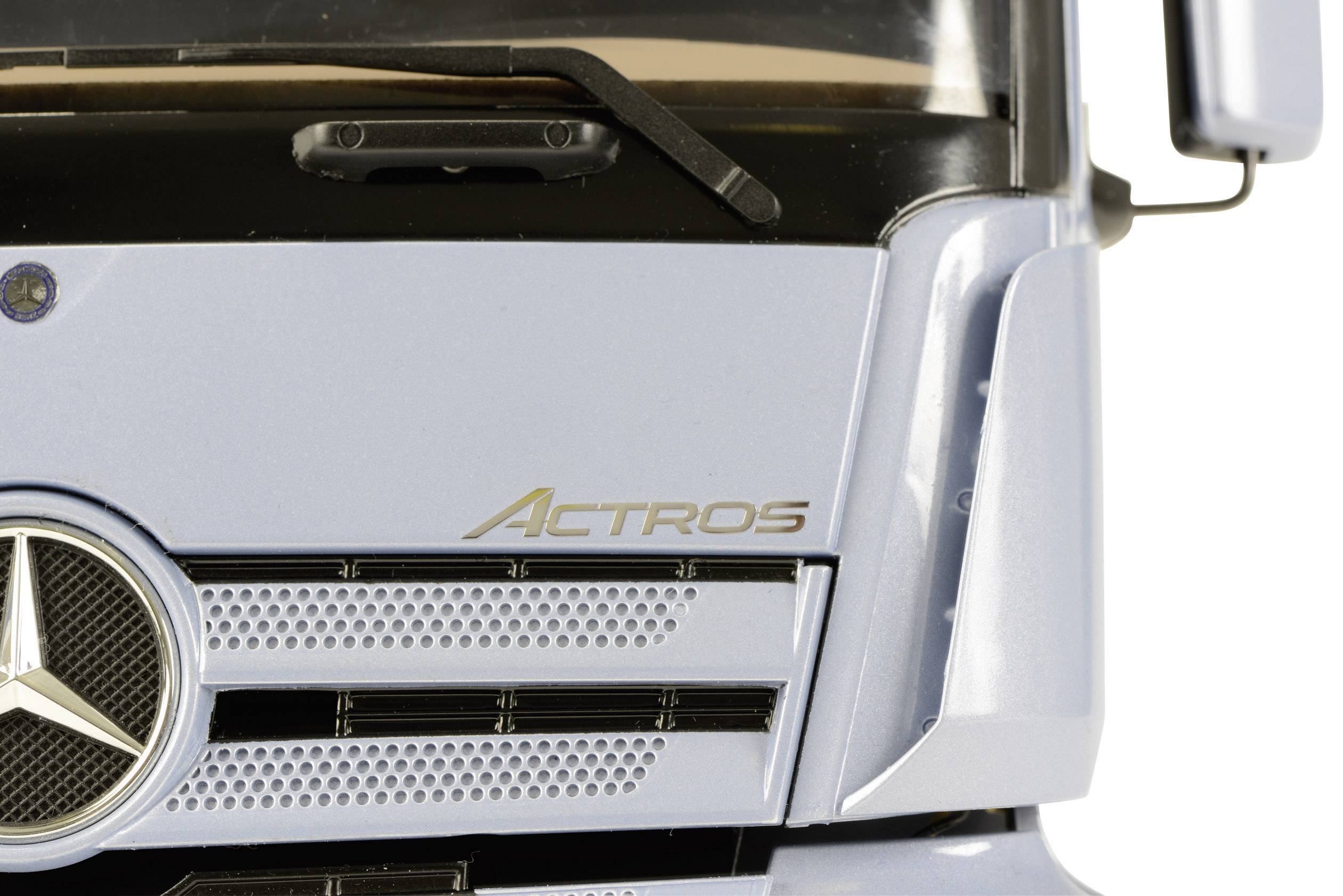 Detailný záber prednej mriežky chladiča nákladného vozidla s nápisom 'Actros' a logom Mercedes-Benz na prednej strane.