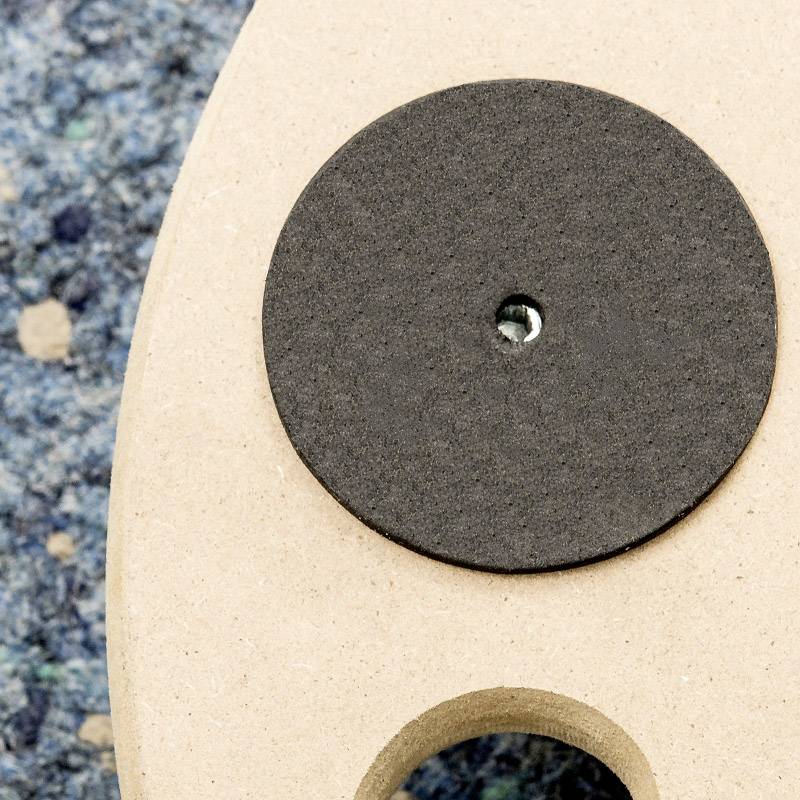Detailný záber otvoru akustickej gitary s čiernym krytom proti spätnej väzbe na vzorovanom koberci.