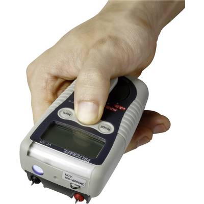 Jedna ruka drží prenosný elektrický merací prístroj s digitálnym displejom.