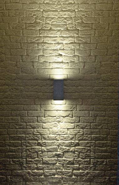 Nástenná lampa na štruktúrovanej kamennej stene, ktorá vyžaruje jemné, žlté svetlo smerom nahor a nadol, čím vytvára teplú atmosféru.
