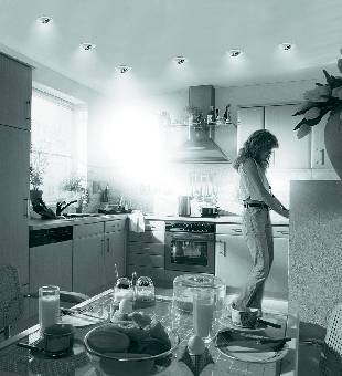 Prestretý raňajkový stôl s pečivom, pomarančovým džúsom, kávou a kvetmi v kaviarni alebo reštaurácii; v pozadí je vidieť osobu.