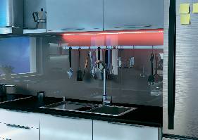 Moderná kuchyňa so drezom a visiacimi skrinkami. Nad pracovnou doskou visia kuchynské náčinie na držiaku, obklopené farebným svetlom.