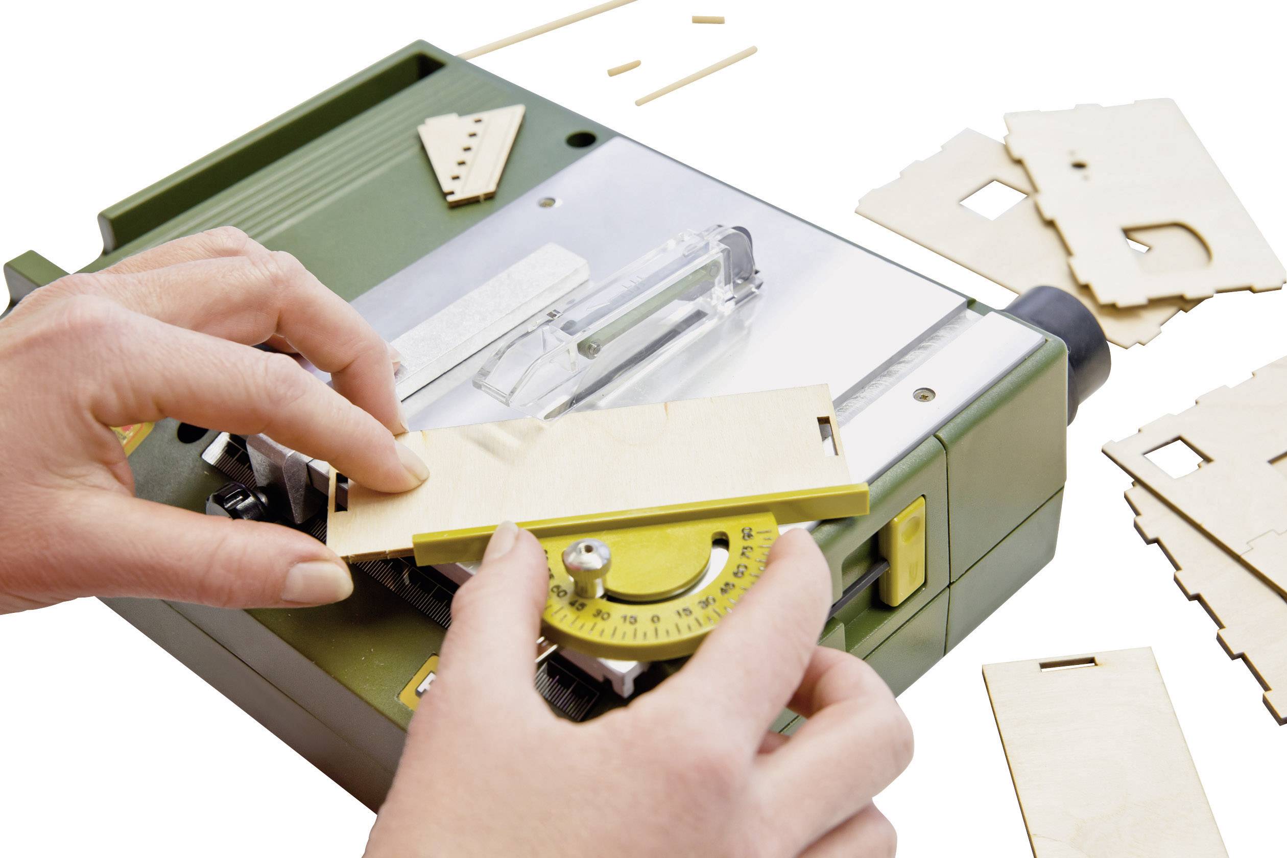 Osoba nastavuje žltý uhlomer na zelenej stolnej kotúčovej píle. Vedľa ležia kúsky dreva a jednotlivé diely.