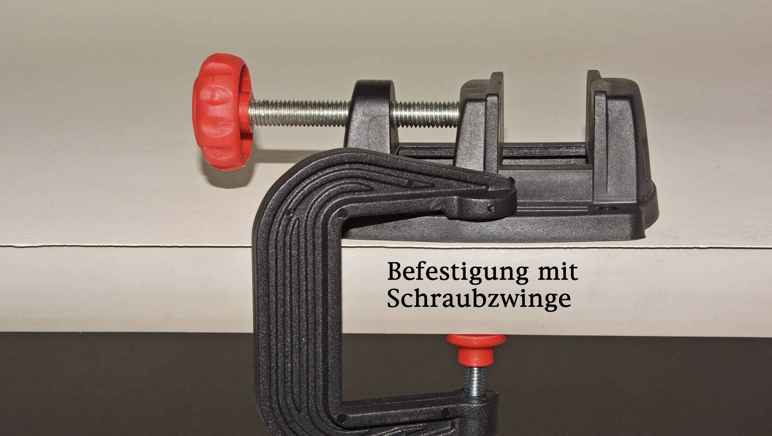 'Strieborná a čierna skrutková svorka fixuje dosku. Červená rukoväť a skrutka hore a dole.'