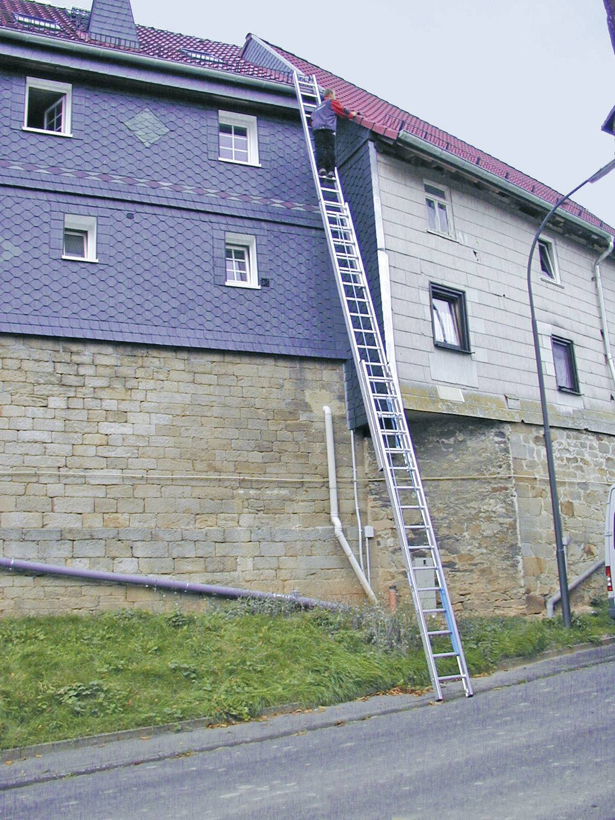 'Dlhý rebrík vedie hore po strmej stene domu.'
