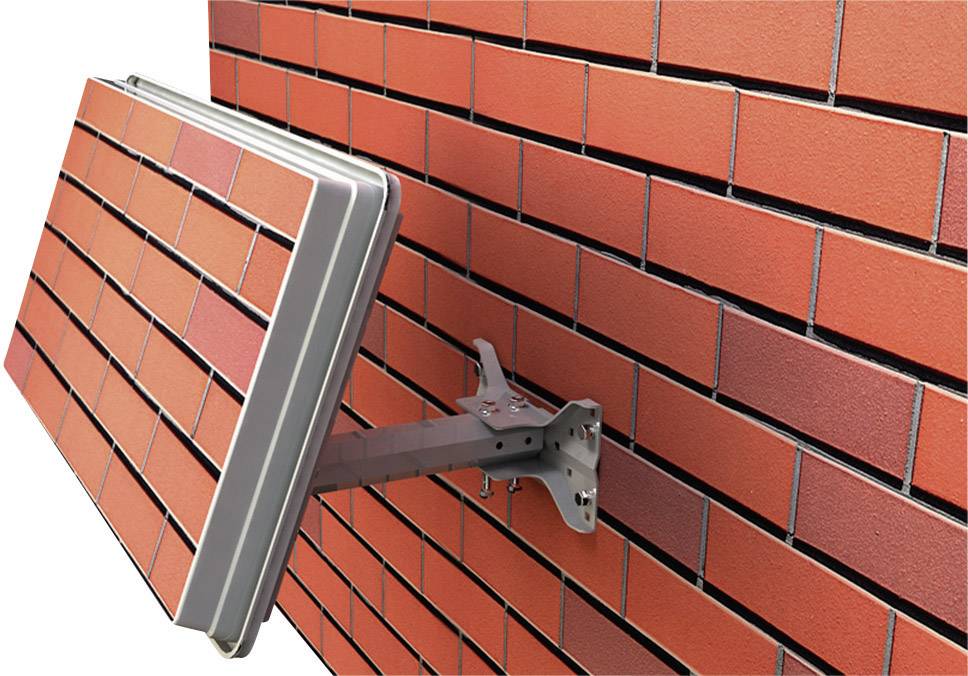 Červený tehlový múr s montážnym ramenom, ktoré drží panel v rovnakom tehlovom štýle.