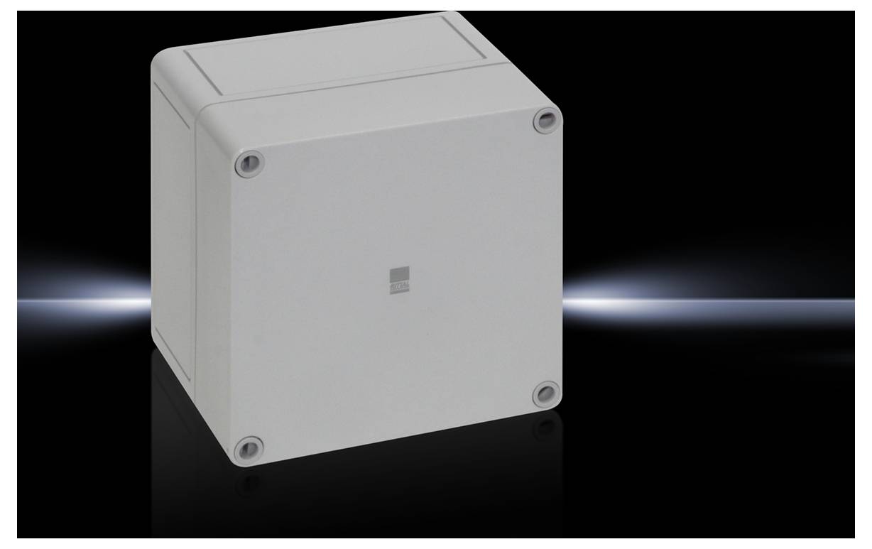 Siva, kvadratna ohišje z zaobljenimi robovi. Stoji pred temnim ozadjem z šibkim svetlobnim žarkom.